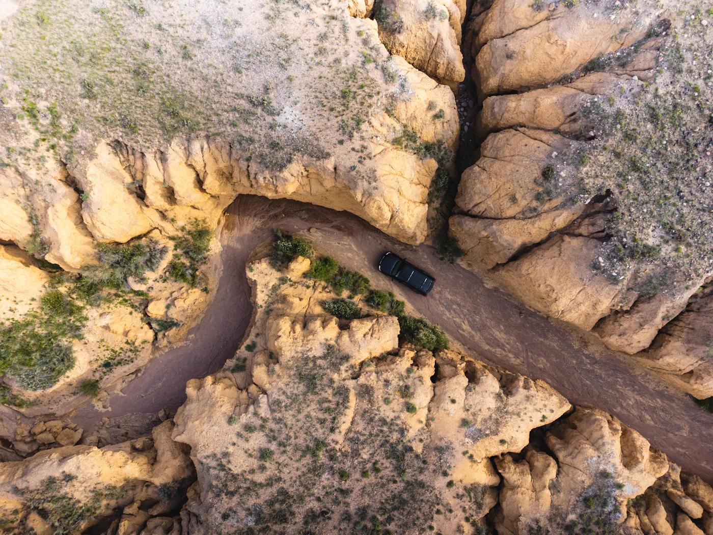 Aerial view of a car driving on a dirt road